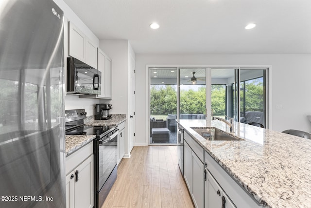 513 Sandstone Dr, Saint Augustine, FL 32086 - kitchen featuring light stone countertops, light wood-style floors, recessed lighting, a sink, and black appliances