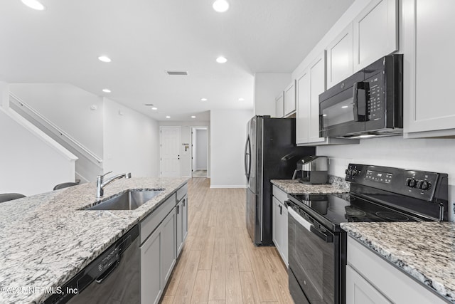 513 Sandstone Dr, Saint Augustine, FL 32086 - kitchen featuring light wood-style floors, a sink, black appliances, and light stone countertops