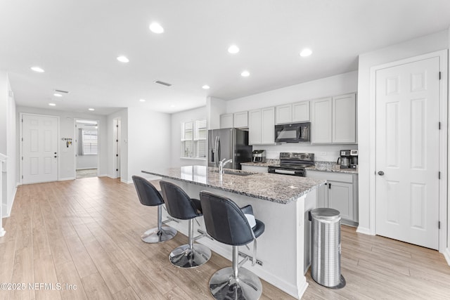513 Sandstone Dr, Saint Augustine, FL 32086 - kitchen featuring visible vents, light stone countertops, black appliances, a breakfast bar, and an island with sink