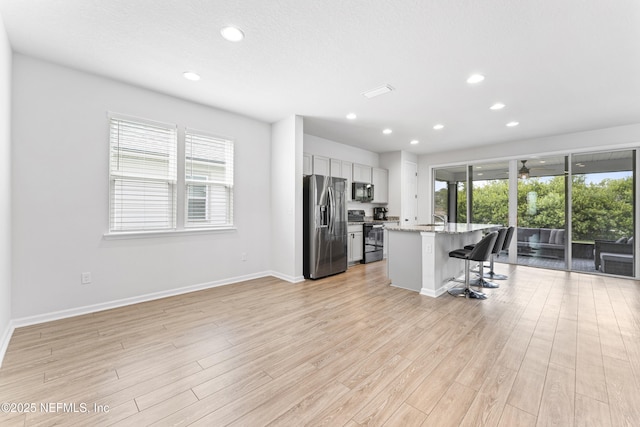 513 Sandstone Dr, Saint Augustine, FL 32086 - kitchen with light wood-type flooring, black appliances, a breakfast bar, and a healthy amount of sunlight