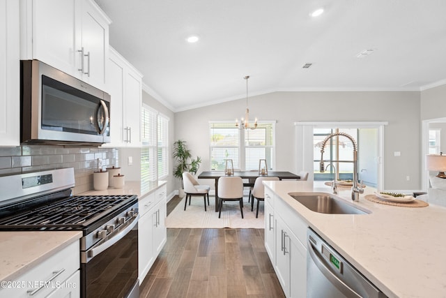 79 Dovetail Cir, Saint Augustine, FL 32095 - kitchen with lofted ceiling, dark wood-style floors, a sink, a notable chandelier, and stainless steel appliances