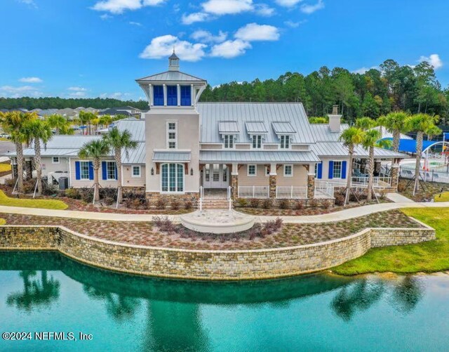rear view of property featuring french doors, a chimney, a standing seam roof, metal roof, and a water view