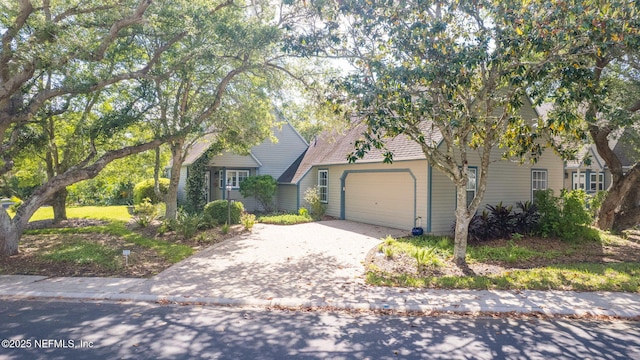 view of property hidden behind natural elements with driveway and a garage