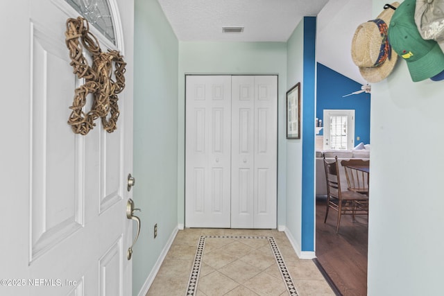 entrance foyer with a textured ceiling, baseboards, visible vents, and light tile patterned flooring