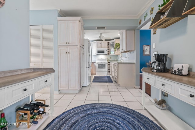 kitchen with a ceiling fan, visible vents, light tile patterned floors, ornamental molding, and white appliances
