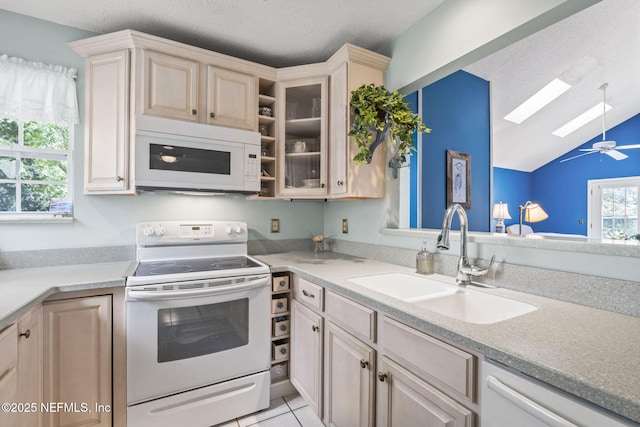 kitchen featuring a sink, white appliances, light countertops, glass insert cabinets, and lofted ceiling with skylight