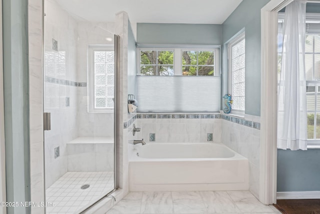 bathroom featuring marble finish floor, a wealth of natural light, a bath, and a stall shower