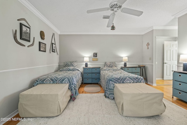 bedroom featuring ceiling fan, a textured ceiling, visible vents, crown molding, and wood finished floors