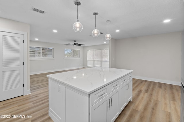 10856 Hawaii Dr S, Jacksonville, FL 32246 - kitchen with visible vents, a kitchen island, ceiling fan, light wood-style flooring, and hanging light fixtures