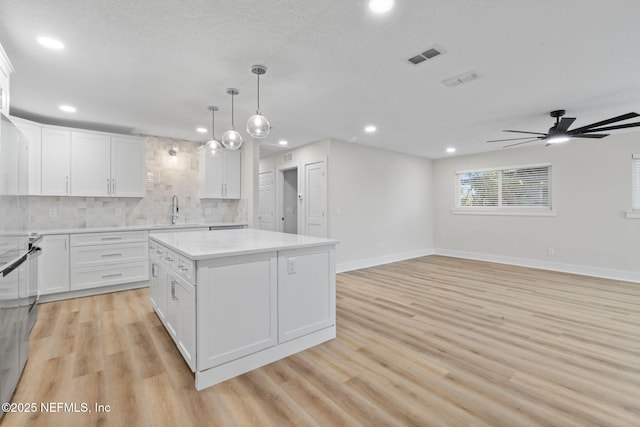 10856 Hawaii Dr S, Jacksonville, FL 32246 - kitchen featuring decorative backsplash, a kitchen island, light countertops, recessed lighting, and light wood-style flooring
