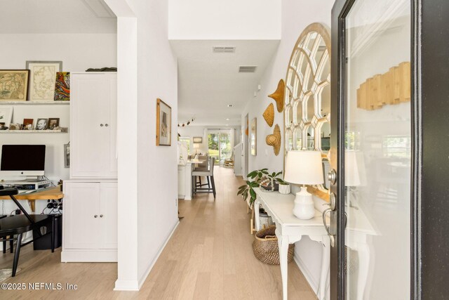 corridor featuring light wood-style floors, baseboards, and visible vents
