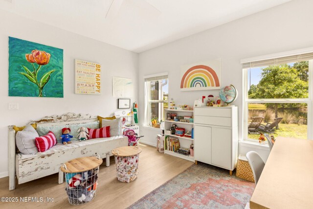 recreation room featuring baseboards, wood finished floors, and a healthy amount of sunlight