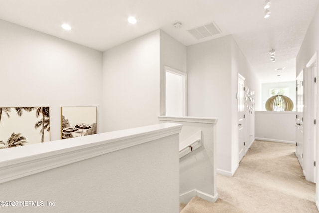 hall with visible vents, baseboards, recessed lighting, light colored carpet, and an upstairs landing