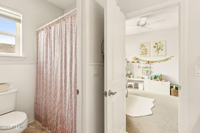 full bath with ceiling fan, wainscoting, toilet, and a shower with shower curtain