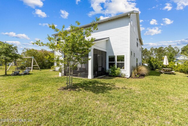 back of house featuring a lawn and a sunroom