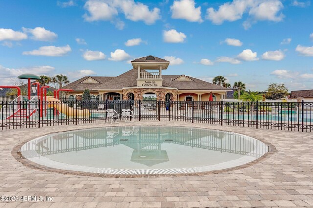 pool with playground community, fence, and a water play area