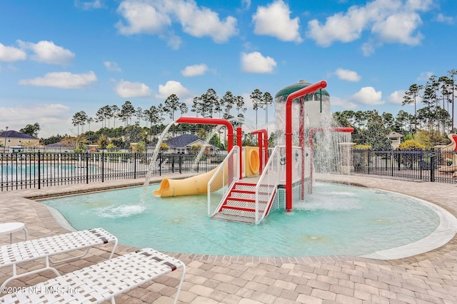 community jungle gym featuring a water play area, fence, and a community pool