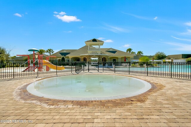communal playground featuring a water play area, fence, and a community pool