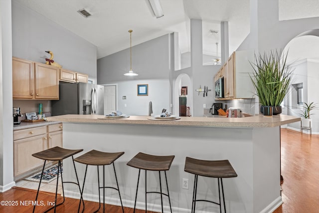 1105 Pine Mill Ln, Ponte Vedra Beach, FL 32082 - kitchen with stainless steel appliances, light brown cabinetry, high vaulted ceiling, a breakfast bar area, and light wood-style flooring