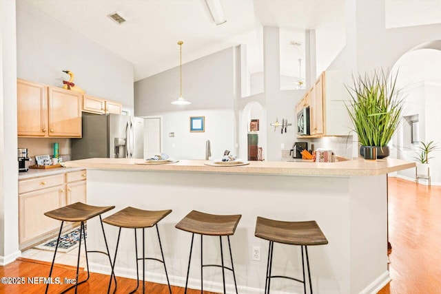 1105 Pine Mill Ln, Ponte Vedra Beach, FL 32082 - kitchen with stainless steel appliances, high vaulted ceiling, light brown cabinets, a breakfast bar, and light wood-type flooring