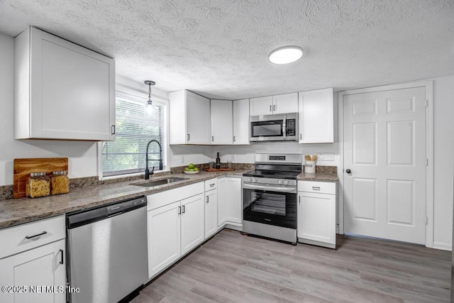 1059 Little Ruth Rd, Green Cove Springs, FL 32043 - kitchen with a textured ceiling, white cabinets, a sink, light wood finished floors, and appliances with stainless steel finishes