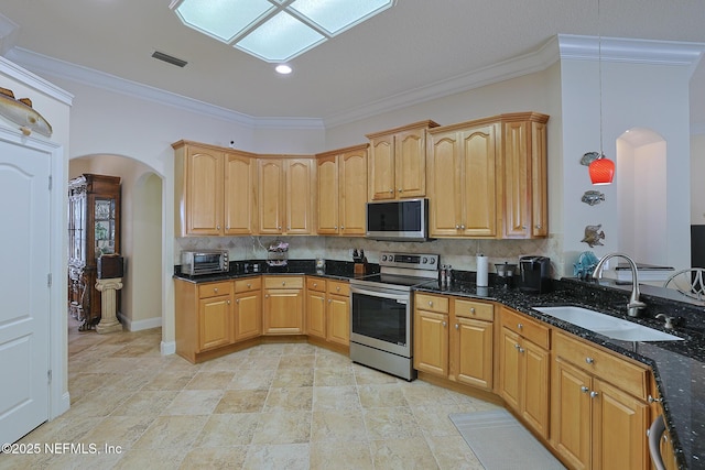 kitchen with visible vents, a sink, arched walkways, dark stone countertops, and stainless steel appliances