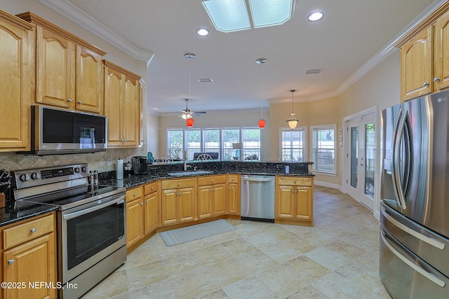 kitchen with a peninsula, dark stone counters, appliances with stainless steel finishes, and ornamental molding