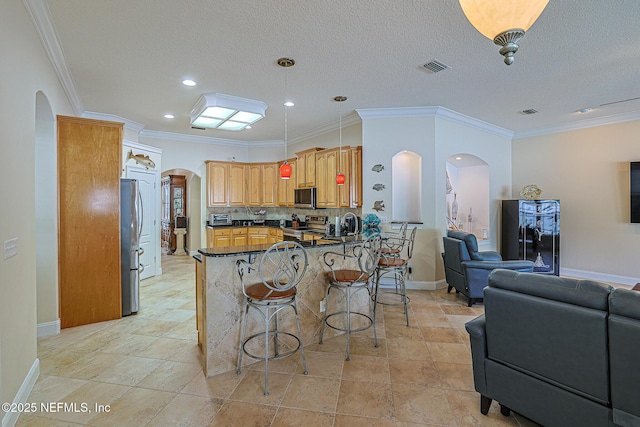 kitchen with arched walkways, a kitchen bar, open floor plan, and stainless steel appliances