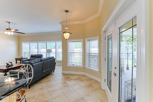 living room featuring ornamental molding, light tile patterned flooring, baseboards, a textured ceiling, and a ceiling fan