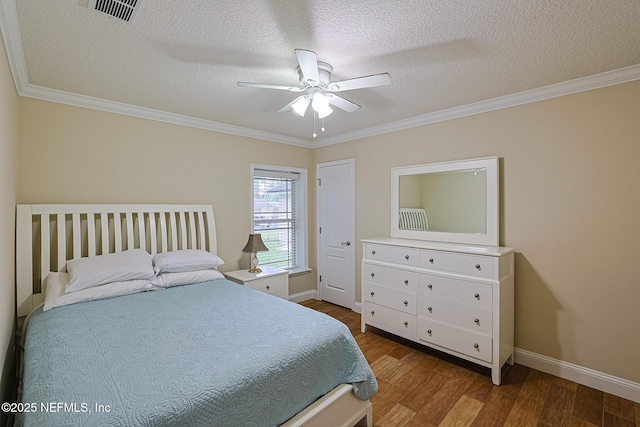 bedroom with a textured ceiling, visible vents, wood finished floors, baseboards, and ornamental molding