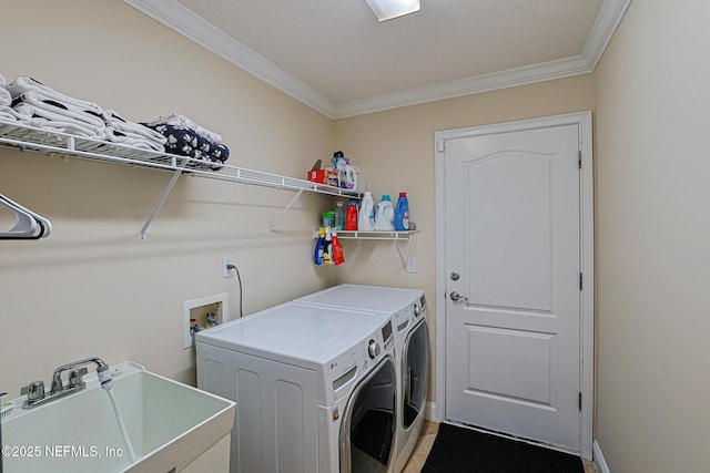 laundry room featuring crown molding, laundry area, a sink, baseboards, and washing machine and dryer