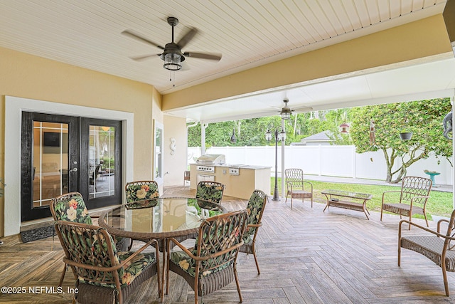 view of patio featuring fence, grilling area, an outdoor kitchen, a ceiling fan, and outdoor dining space