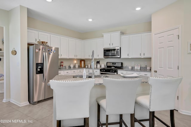 497 Coastline Way, Saint Augustine, FL 32092 - kitchen featuring stainless steel appliances, white cabinetry, light tile patterned floors, a breakfast bar area, and an island with sink