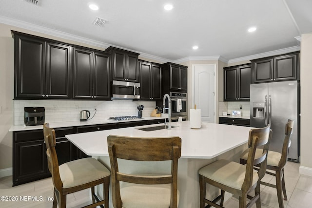 149 San Telmo Ct, Saint Augustine, FL 32095 - kitchen with a sink, stainless steel appliances, an island with sink, decorative backsplash, and dark cabinetry