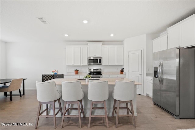 115 Beauclair Blvd, Saint Augustine, FL 32084 - kitchen featuring visible vents, a breakfast bar, a center island with sink, light wood-style flooring, and appliances with stainless steel finishes