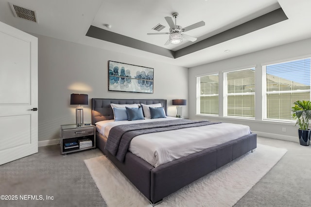 bedroom featuring ceiling fan, visible vents, baseboards, a raised ceiling, and carpet