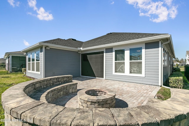 rear view of property with a patio, fence, a shingled roof, and an outdoor fire pit