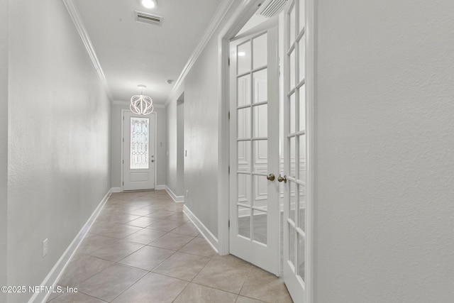 doorway with visible vents, ornamental molding, baseboards, light tile patterned floors, and a notable chandelier