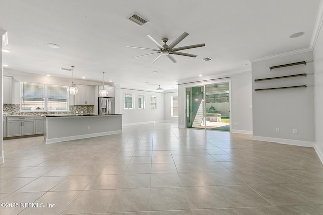 unfurnished living room featuring a ceiling fan, visible vents, ornamental molding, and light tile patterned floors