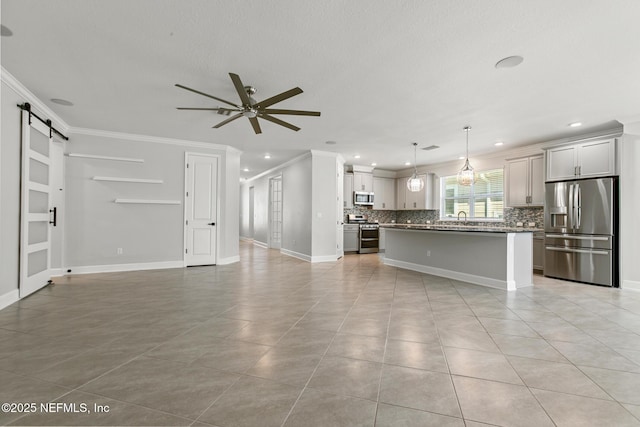 unfurnished living room featuring ceiling fan, crown molding, a barn door, light tile patterned floors, and a sink
