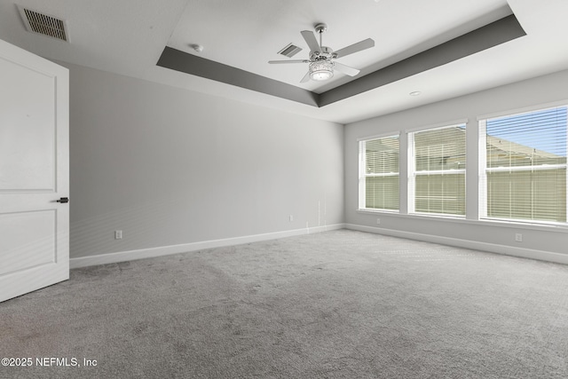 carpeted spare room featuring baseboards, a ceiling fan, a raised ceiling, and visible vents