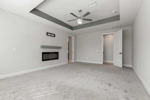 unfurnished living room with visible vents, carpet flooring, a raised ceiling, and a ceiling fan