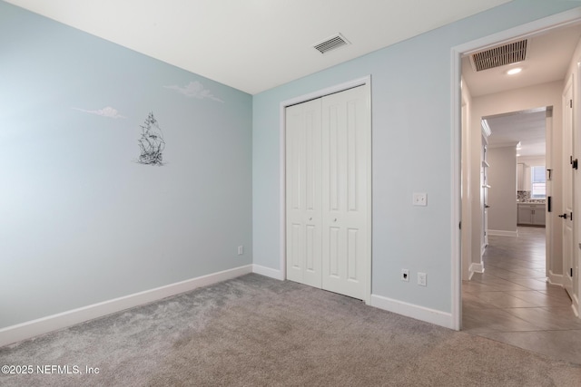 unfurnished bedroom featuring baseboards, visible vents, carpet, and a closet