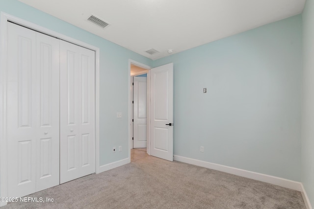 unfurnished bedroom featuring baseboards, carpet flooring, visible vents, and a closet