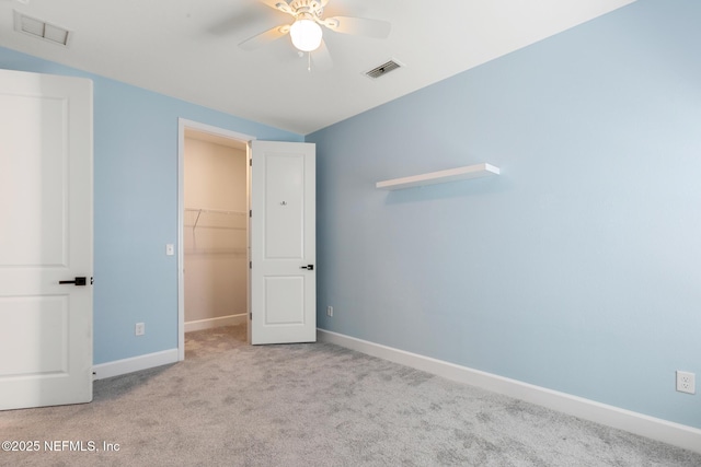 unfurnished bedroom featuring a spacious closet, baseboards, carpet, and visible vents