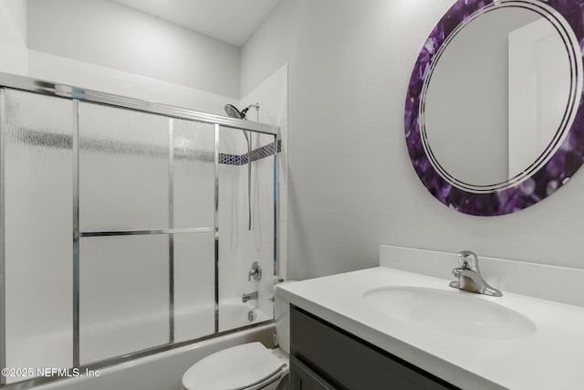 bathroom featuring toilet, bath / shower combo with glass door, and vanity