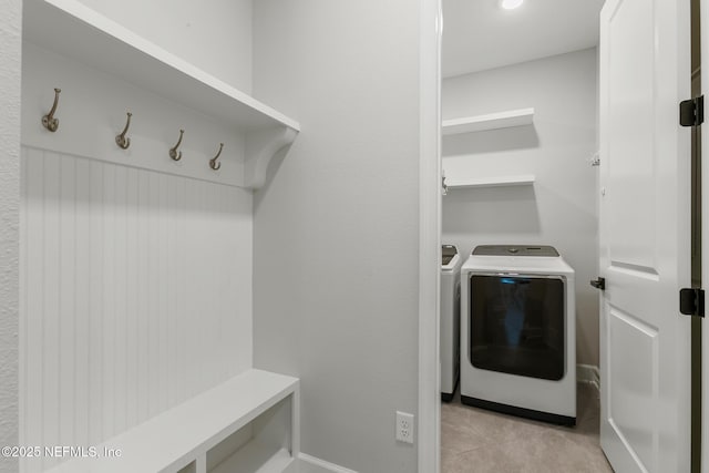 clothes washing area featuring laundry area, baseboards, independent washer and dryer, and light tile patterned floors