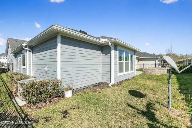 view of property exterior with a lawn and fence