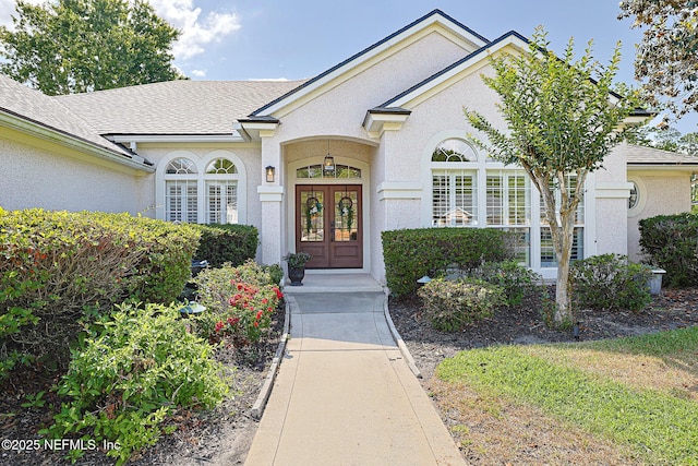 doorway to property featuring a shingled roof, stucco siding, and french doors