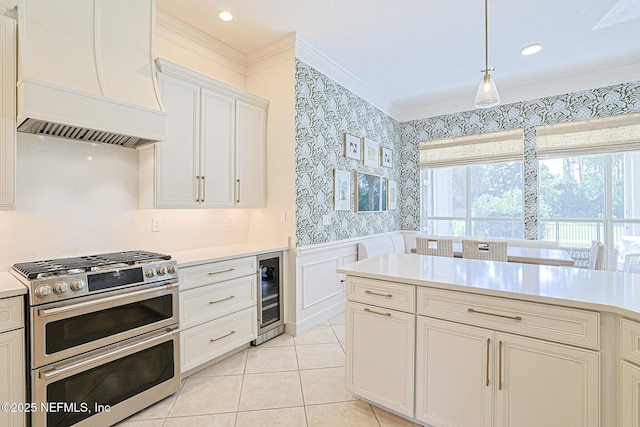 kitchen featuring wallpapered walls, beverage cooler, range with two ovens, premium range hood, and crown molding